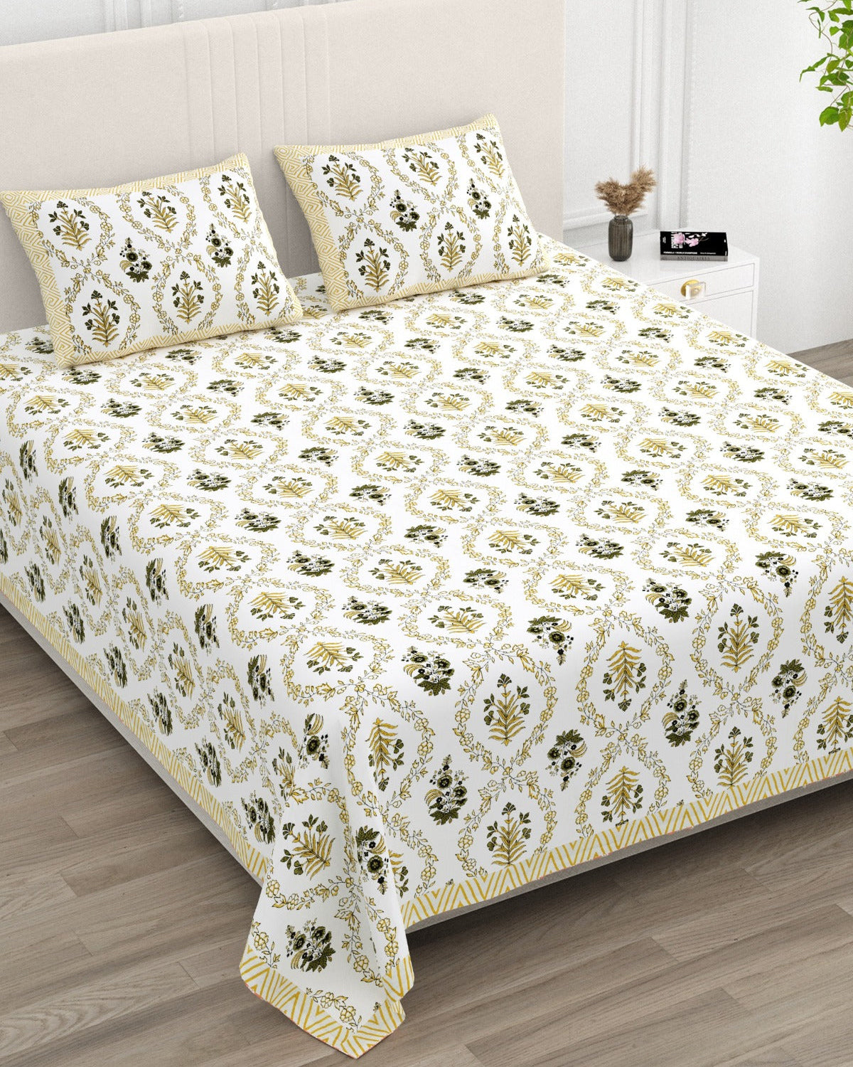 Parijat Yellow bedsheet, white floral ogee jaal with dark olive flowers, in a studio shot against a cream headboard