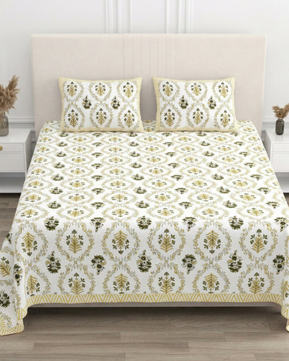 Parijat Yellow bedsheet, white floral ogee jaal with dark olive flowers, in a studio shot against a cream headboard