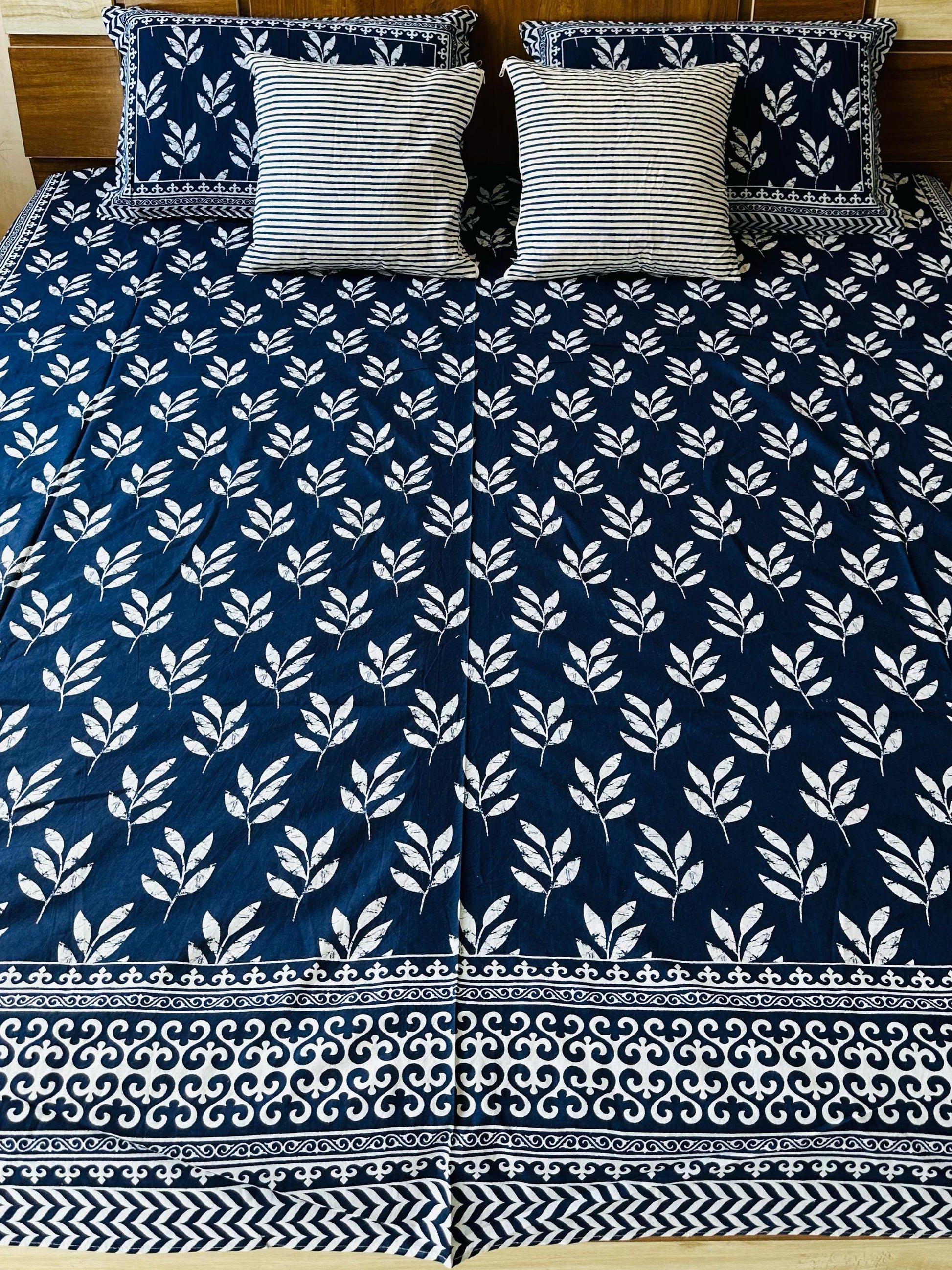 Bed with blue and white patterned bedspread and matching pillows.