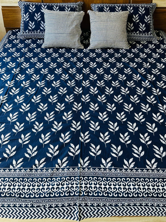 Bed with blue and white patterned bedspread and matching pillows.