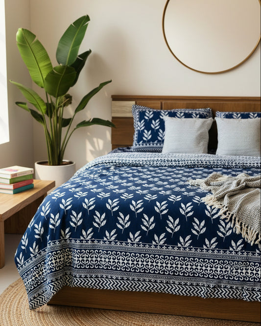 Bed with blue and white patterned bedspread and matching pillows.