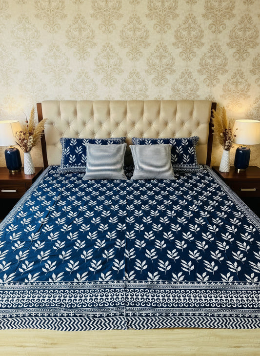 Bed with blue and white patterned bedspread and matching pillows.