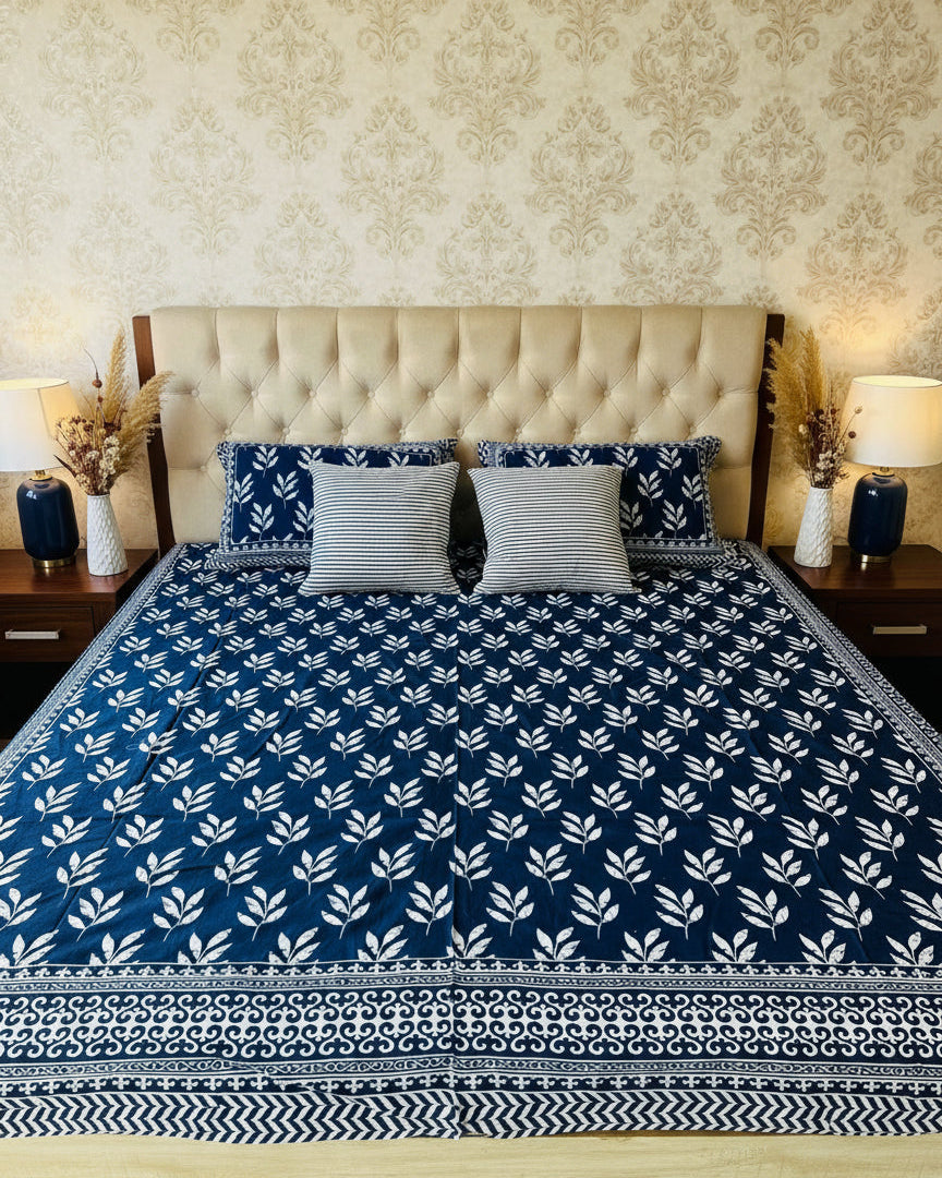 Bed with blue and white patterned bedspread and matching pillows.