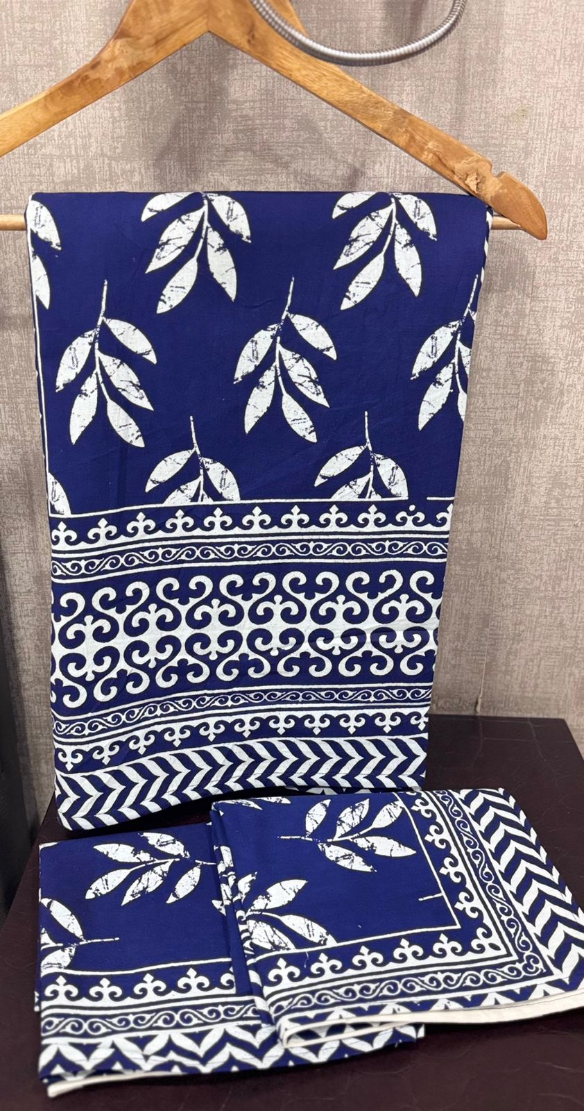 Blue fabric with white patterns on a wooden hanger against a gray wall.