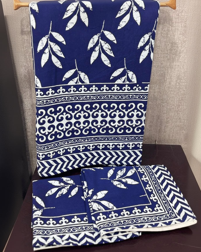 Blue fabric with white patterns on a wooden hanger against a gray wall.