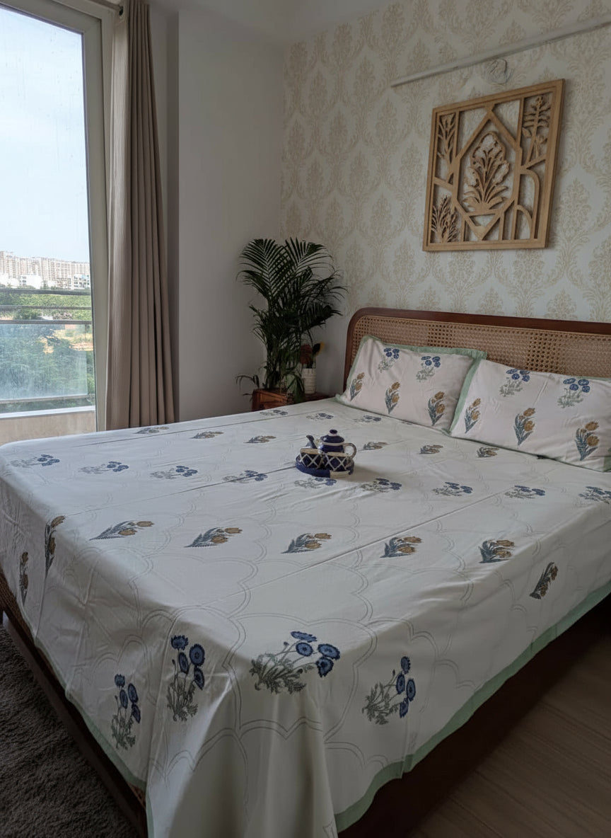Bedroom with floral-patterned bedspheet and pillows, overlooking a scenic view.