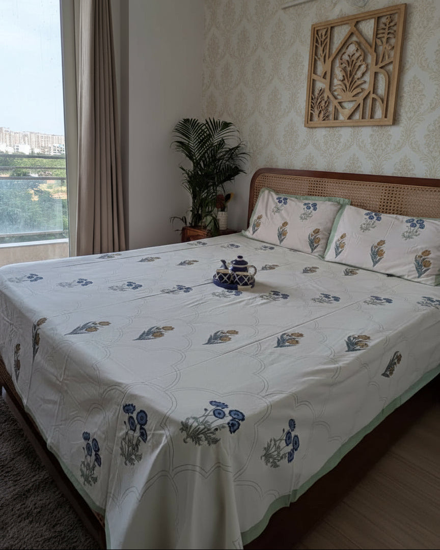 Bedroom with floral-patterned bedspheet and pillows, overlooking a scenic view.