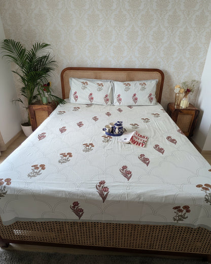Rust floral booti cotton bedsheet with a grey scalloped pattern on a cane bed