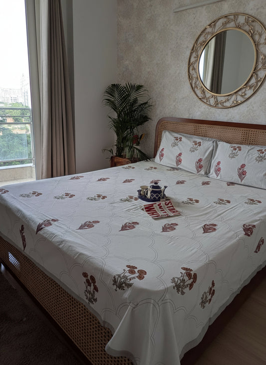 Bed with floral bedding in a room with a window and plant