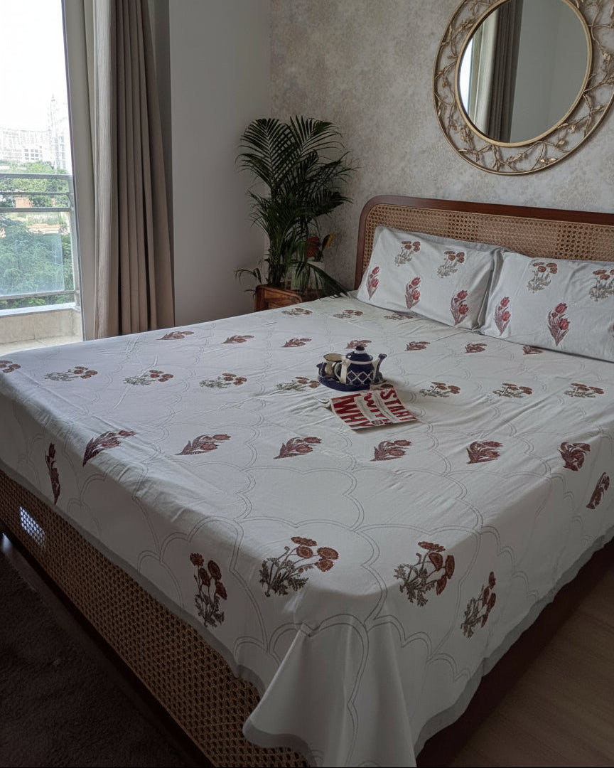 Bed with floral bedding in a room with a window and plant