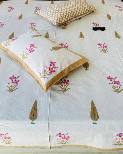 Close-up of ivory cotton fabric with pink orchid florals, gold cypress motifs and a gold trellis pillow cover