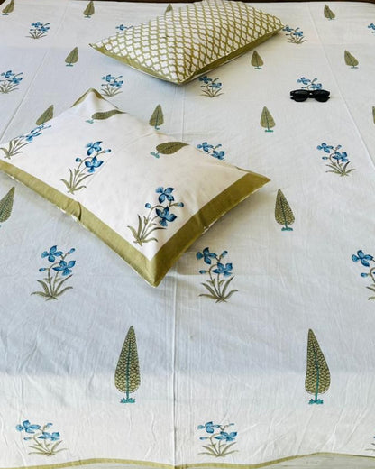 Close-up of ivory cotton fabric with blue orchid florals, olive cypress motifs and an olive trellis pillow cover