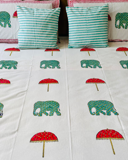 Close-up of white cotton fabric with green hand block elephants and red parasol print