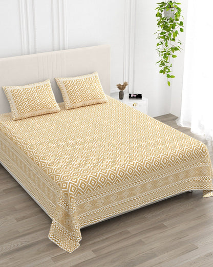 Ratna Beige bedsheet, all-over mustard-ochre nested-diamond print, in a studio shot against a cream headboard