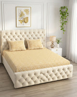 Ratna Beige bedsheet, all-over mustard-ochre nested-diamond print, on a tufted ivory bed