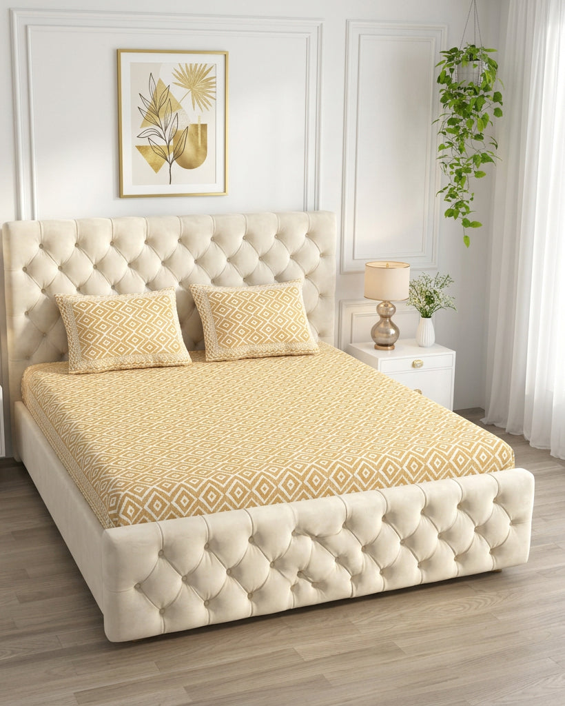 Ratna Beige bedsheet, all-over mustard-ochre nested-diamond print, on a tufted ivory bed