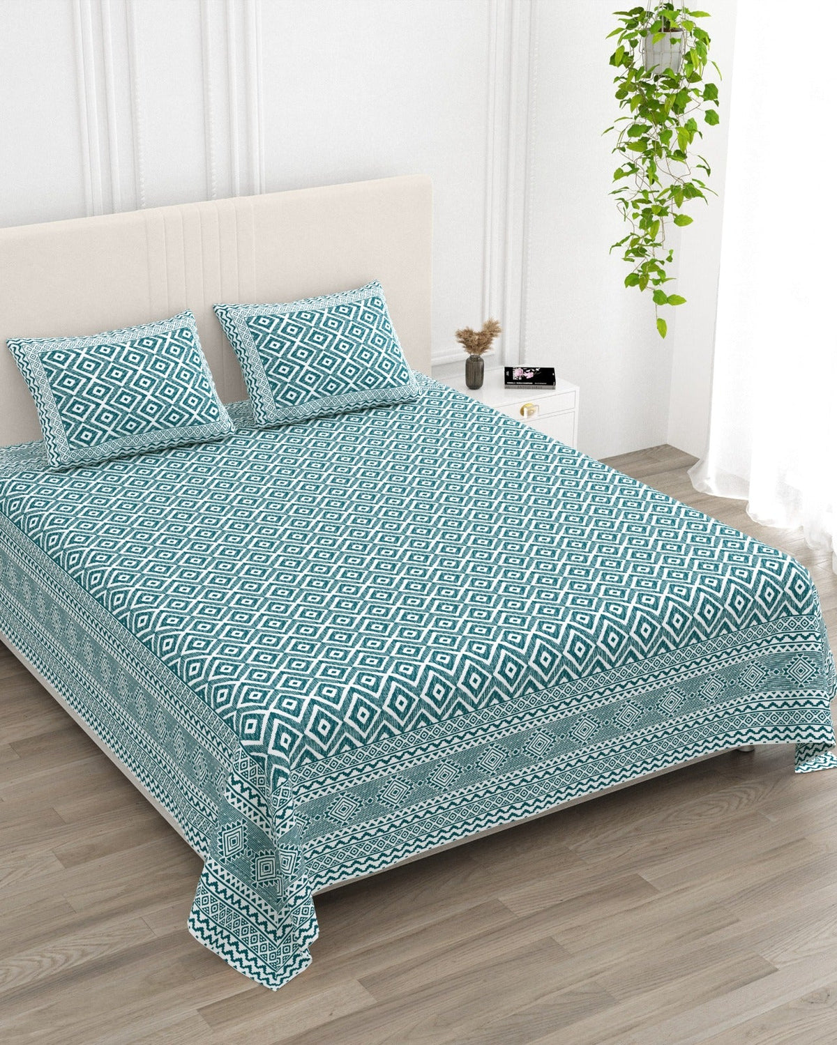 Ratna Blue bedsheet, all-over teal nested-diamond print, in a studio shot against a cream headboard