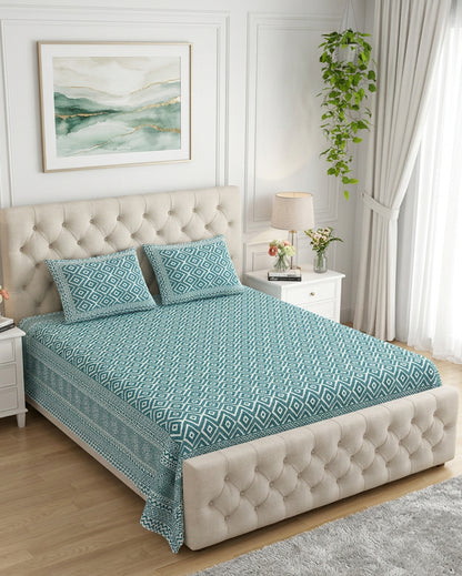 Ratna Blue bedsheet, all-over teal nested-diamond print, on a bed with a tufted cream headboard