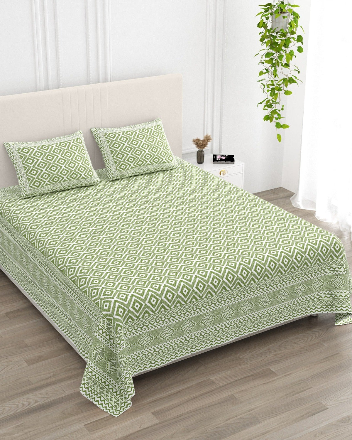 Ratna Green bedsheet, all-over sage-green nested-diamond print, in a studio shot against a cream headboard