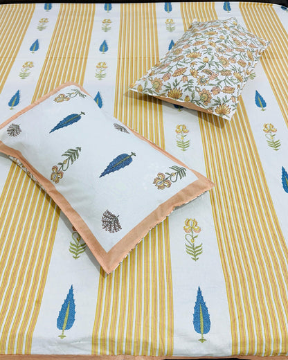 Mustard striped cotton bedsheet with blue botanical motifs and a peach-bordered pillow cover