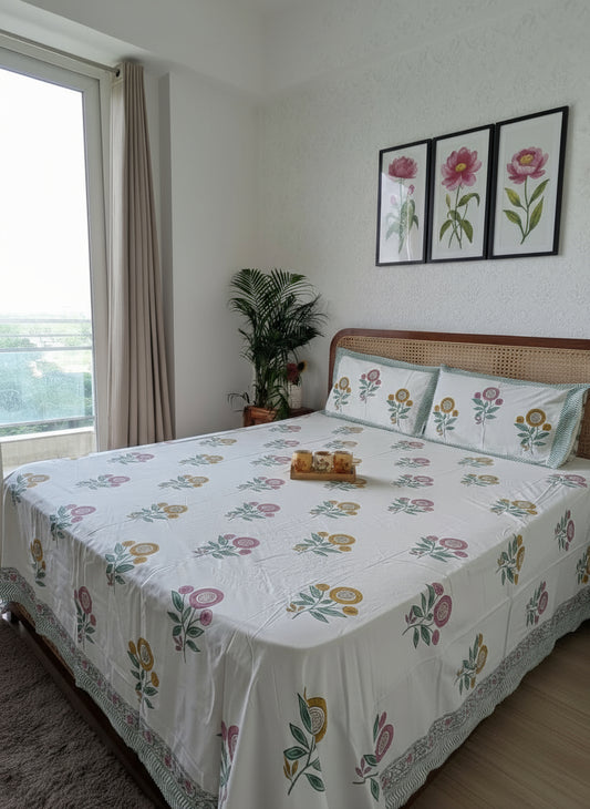 Bed with floral bedding in a room with a window and plant