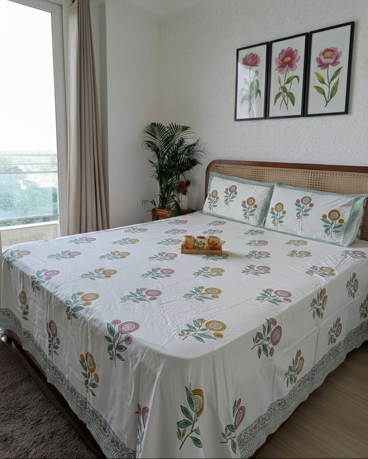 Bed with floral bedding in a room with a window and plant