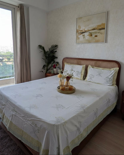 Delicate green floral hand block cotton bedsheet on white with a yellow-green border