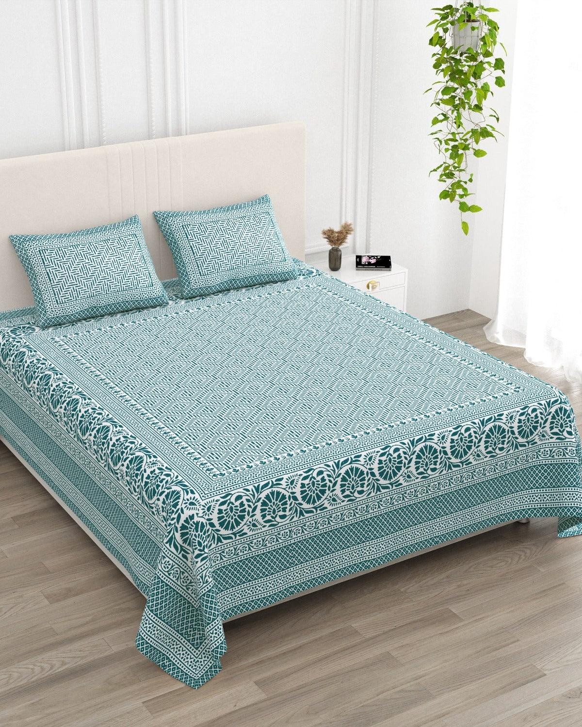 Sagar Blue bedsheet, teal geometric maze with a medallion-flower border, in a studio shot against a cream headboard