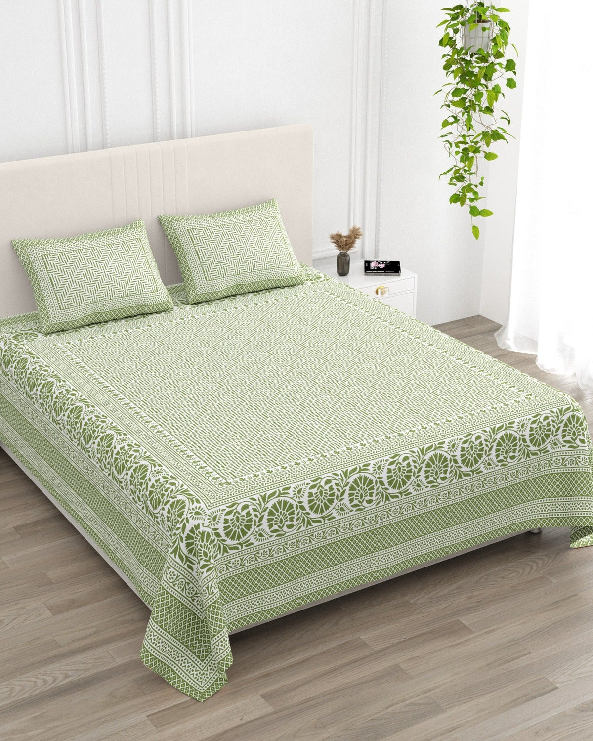 Sagar Green bedsheet, sage-green geometric maze with a medallion-flower border, in a studio shot against a cream headboard