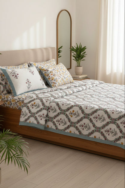 Bed with floral patterned bedsheet and 2 reversible matching pillows in blue, yellow & red