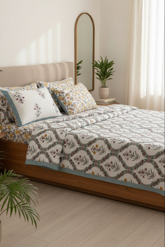 Bed with floral patterned bedsheet and 2 reversible matching pillows in blue, yellow & red