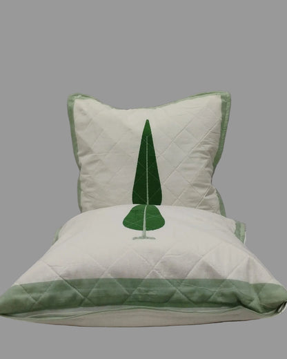 Two Suparna green quilted cushion covers stacked to show the tree motif and green trim