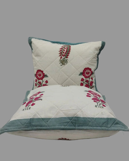 Two Surmayi blue quilted cushion covers stacked to show the floral print and teal trim