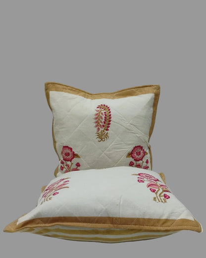 Two Surmayi cushion covers stacked to show pink floral motifs and mustard trim