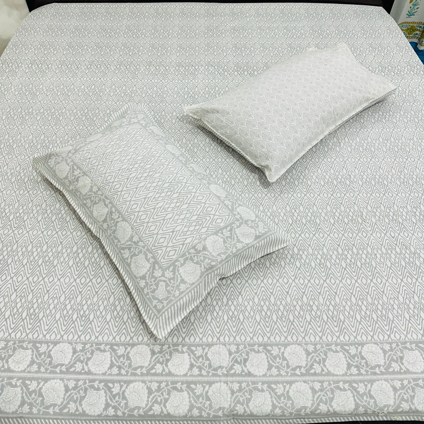 Gray patterned bedspread with matching pillows on a bed