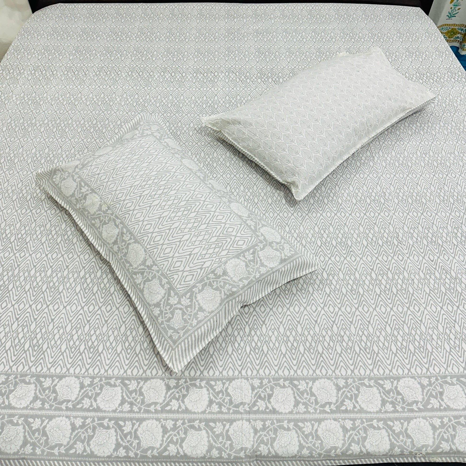 Gray patterned bedspread with matching pillows on a bed