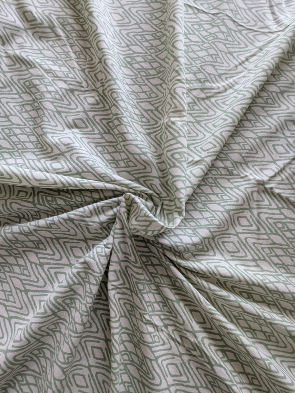 Close-up of patterned bedsheet cotton fabric with geometric design in green