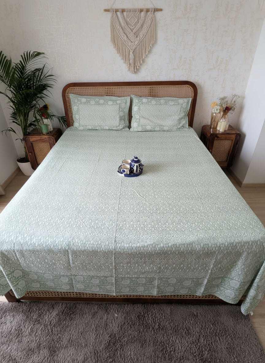 Bed with green patterned bedsheet and reversible pillows in green