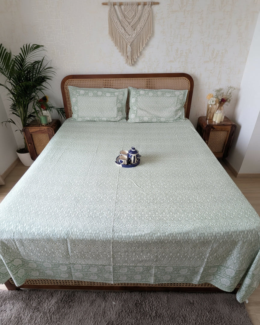 Bed with green patterned bedsheet and reversible pillows in green