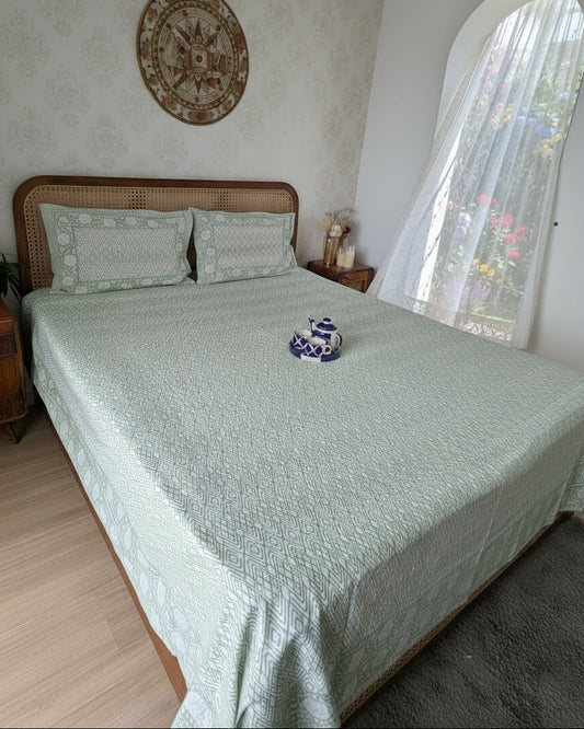 Bed with green bedsheet and a small decorative item in a room