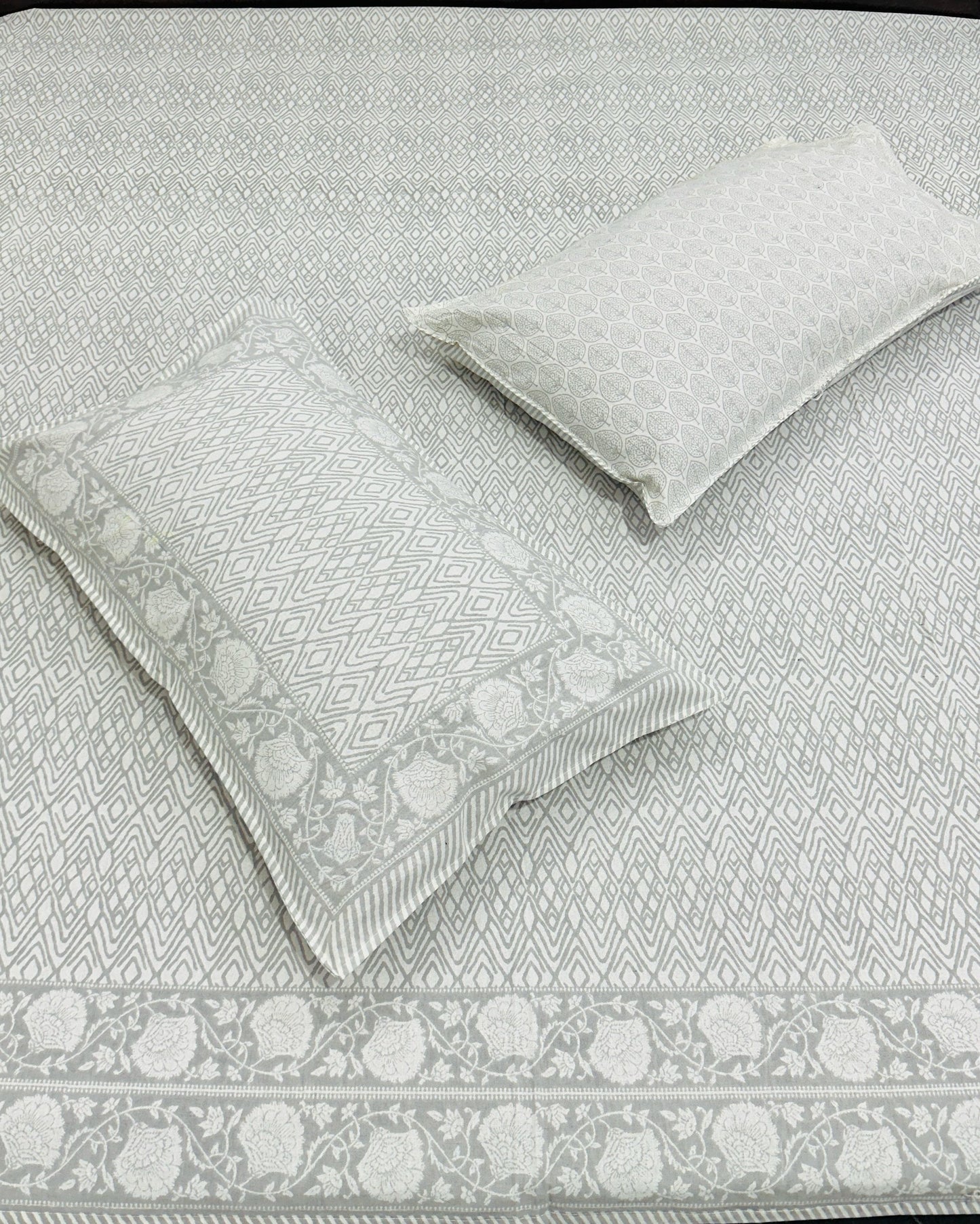 Gray patterned bedspread with matching pillows on a bed