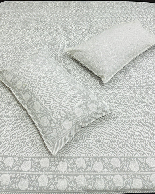 Gray patterned bedspread with matching pillows on a bed