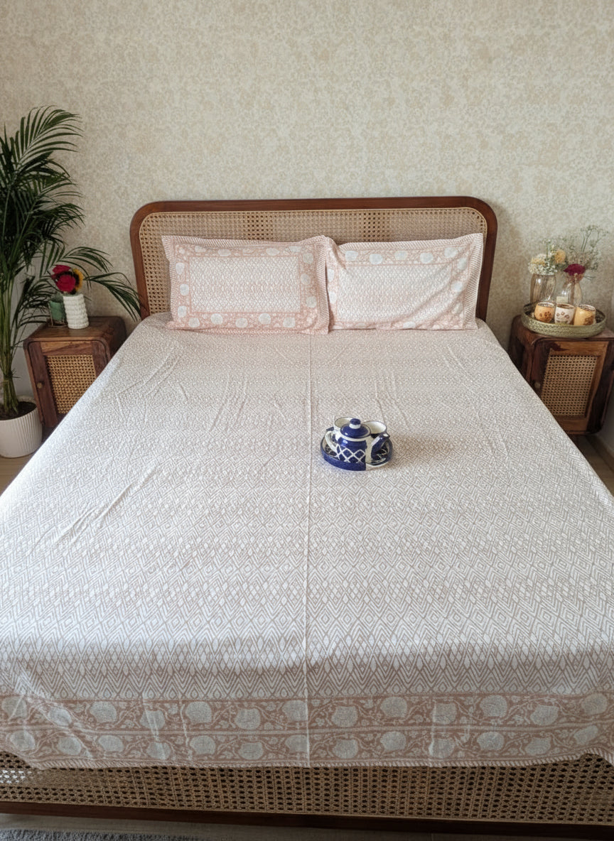 Bed with white and peach bedsheet and peach pillows in a bedroom setting.