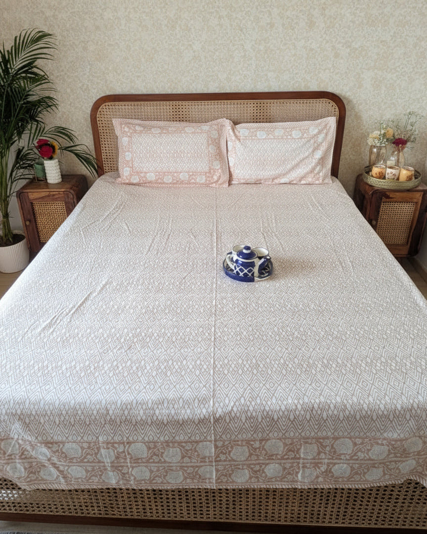 Bed with white and peach bedsheet and peach pillows in a bedroom setting.
