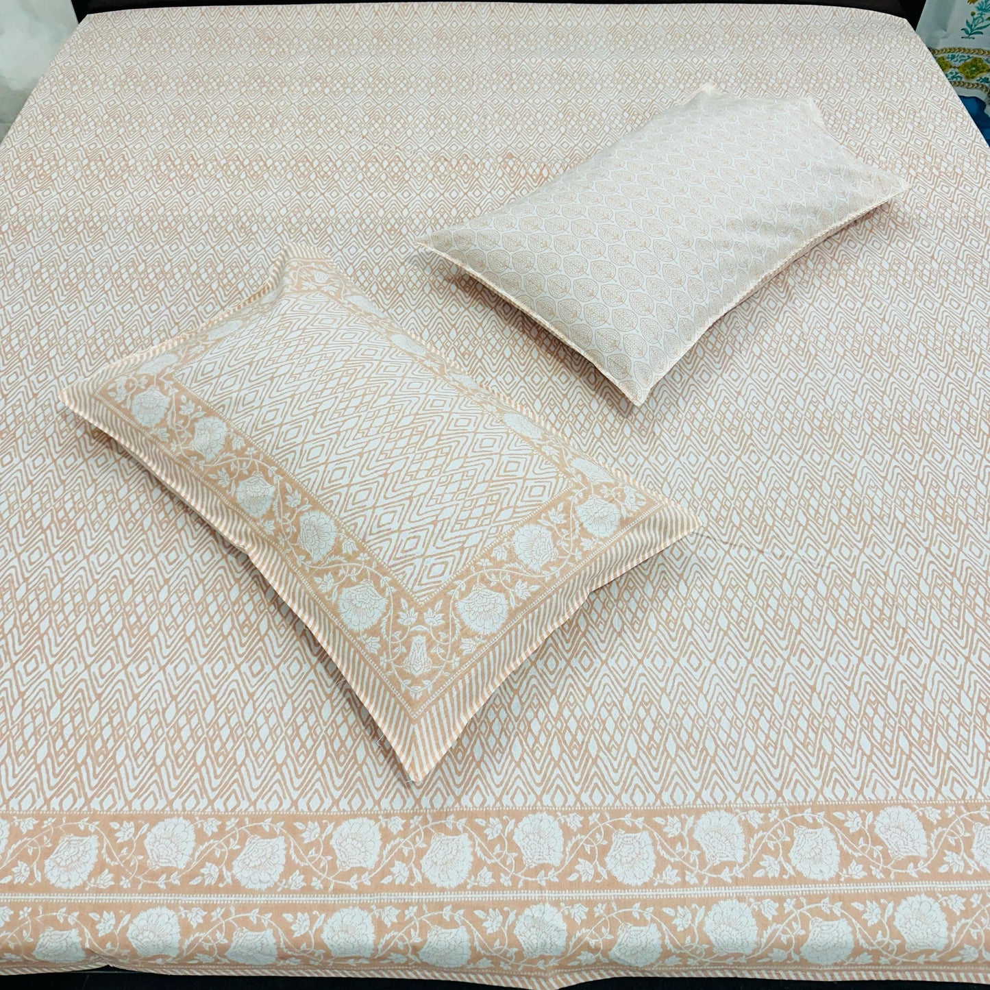 Peach and white patterned bedspread with matching pillow on a bed