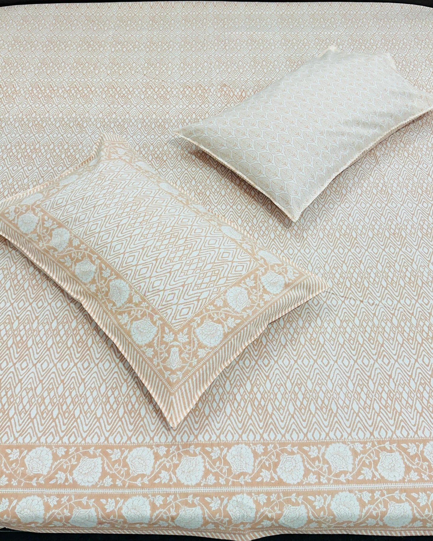 Peach and white patterned bedspread with matching pillow on a bed