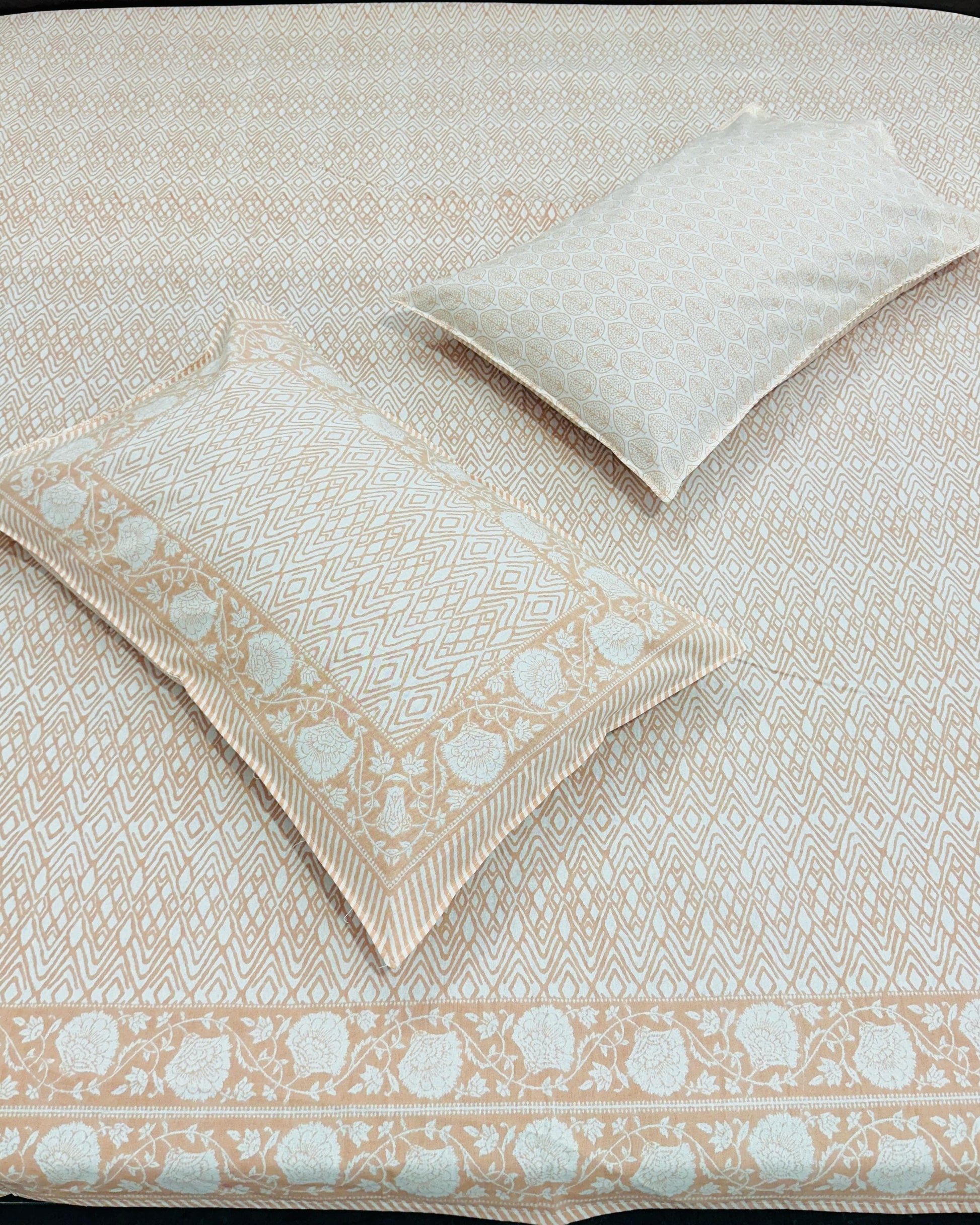 Peach and white patterned bedspread with matching pillow on a bed