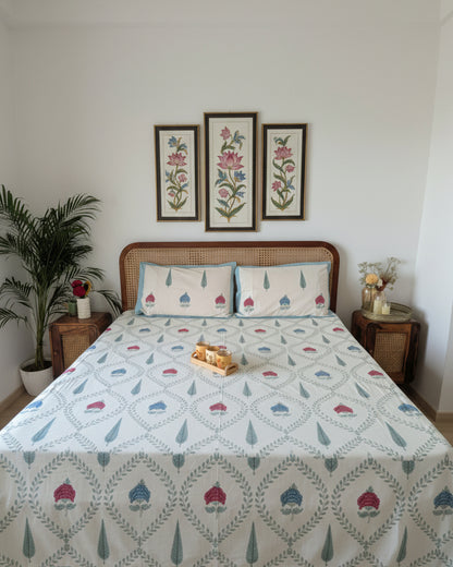 Teal blue lotus motif cotton bedsheet with a vine trellis on ivory, on a cane bed