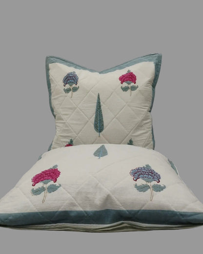 Two Tarangini blue quilted cushion covers stacked to show the floral print and teal trim