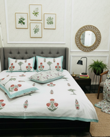 Coral floral and green palm motif soft fine cotton bedsheet styled on a grey tufted bed